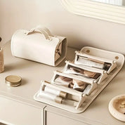 Borsa organizer per trucchi in pelle bianca, con scomparti trasparenti, su tavolo da trucco beige. Accessorio elegante per cosmetici.