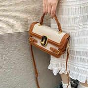 Borsa a tracolla in pelle marrone e tessuto beige, design elegante con chiusura dorata, indossata da una persona in abito bianco plissettato.