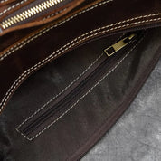 Interno di una borsa in pelle marrone con cerniera dorata e cuciture bianche. Design elegante, ideale per moda e accessori di lusso.
