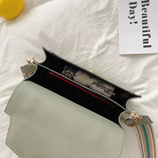 Borsa a tracolla verde chiaro aperta, con interno visibile e accessori. Design elegante, perfetta per moda femminile e uso quotidiano.
