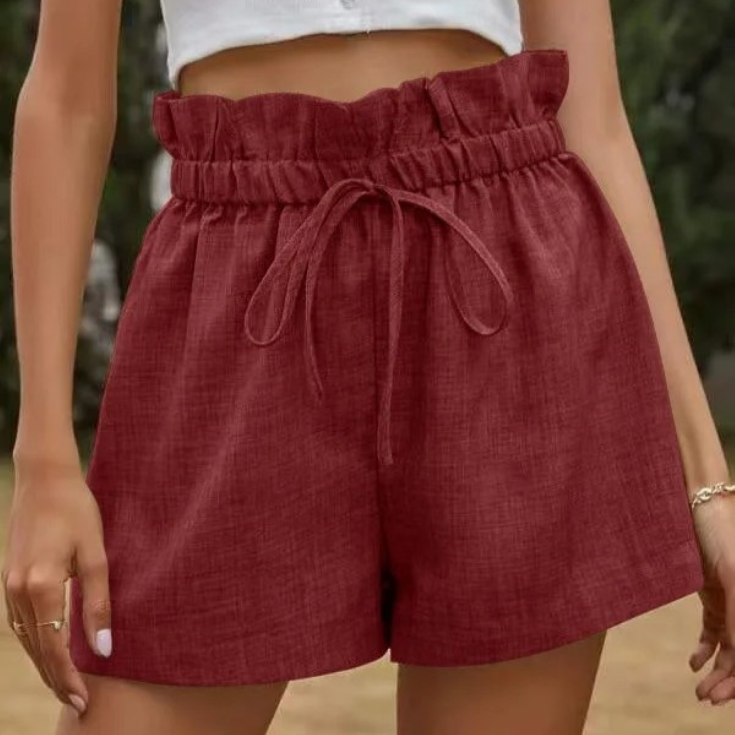 Shorts rossi a vita alta con cintura arricciata, indossati da una donna. Moda estiva casual, tessuto leggero, ideale per look trendy e confortevoli.