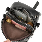 Zaino nero in pelle con cerniera aperta, contenente smartphone, occhiali, rossetto e flaconi. Accessori moda, pratico e compatto.