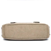 Borsa a tracolla in tela beige, vista dal basso, con design rettangolare e chiusure a fibbia. Accessorio moda casual, resistente e versatile.
