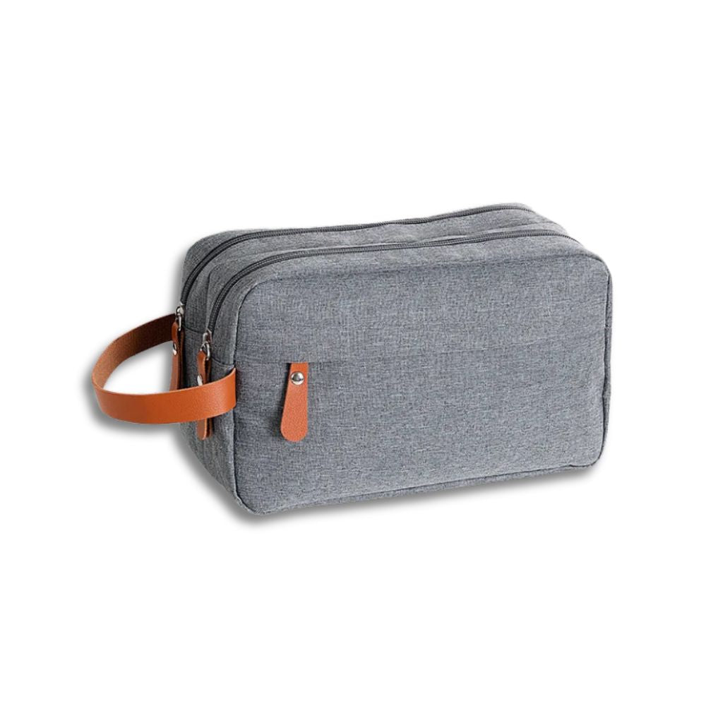 Borsa da toilette grigia in tessuto con manico in pelle marrone, doppia cerniera. Elegante e pratica per viaggi, accessori bagno, organizer.
