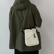 Giacca verde con cappuccio e borsa a tracolla bianca, design casual, moda urbana, abbigliamento autunnale, stile unisex, tessuto impermeabile.