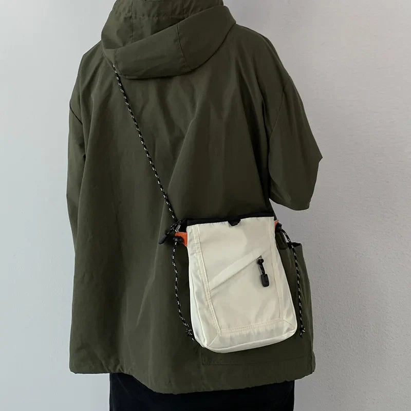Giacca verde con cappuccio e borsa a tracolla bianca, design casual, moda urbana, abbigliamento autunnale, stile unisex, tessuto impermeabile.