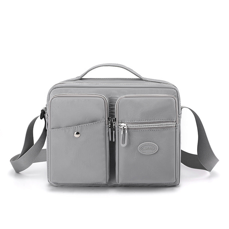 Borsa a tracolla grigia in pelle sintetica con tasche multiple e cerniere, design elegante e funzionale, ideale per uomo e donna.