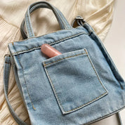 Borsa a tracolla in denim con tasca frontale, contenente un rossetto rosa. Design casual, perfetta per moda quotidiana e accessori femminili.