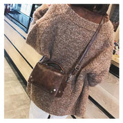 Donna con maglione marrone e borsa a tracolla in pelle marrone, stile casual autunnale, moda femminile, accessori eleganti, shopping urbano.