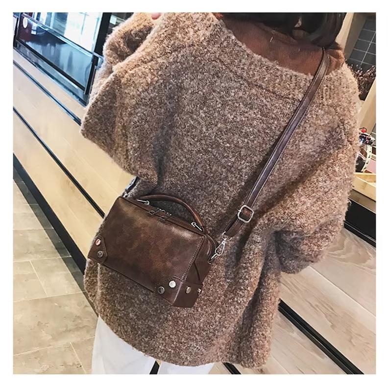 Donna con maglione marrone e borsa a tracolla in pelle marrone, stile casual autunnale, moda femminile, accessori eleganti, shopping urbano.