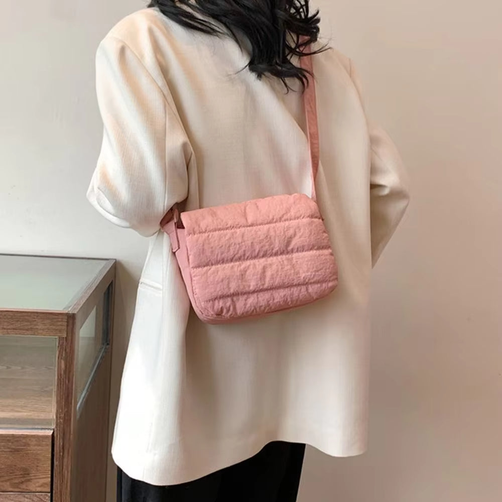 Donna con giacca beige indossa borsa a tracolla rosa trapuntata. Accessorio moda femminile, stile casual chic.