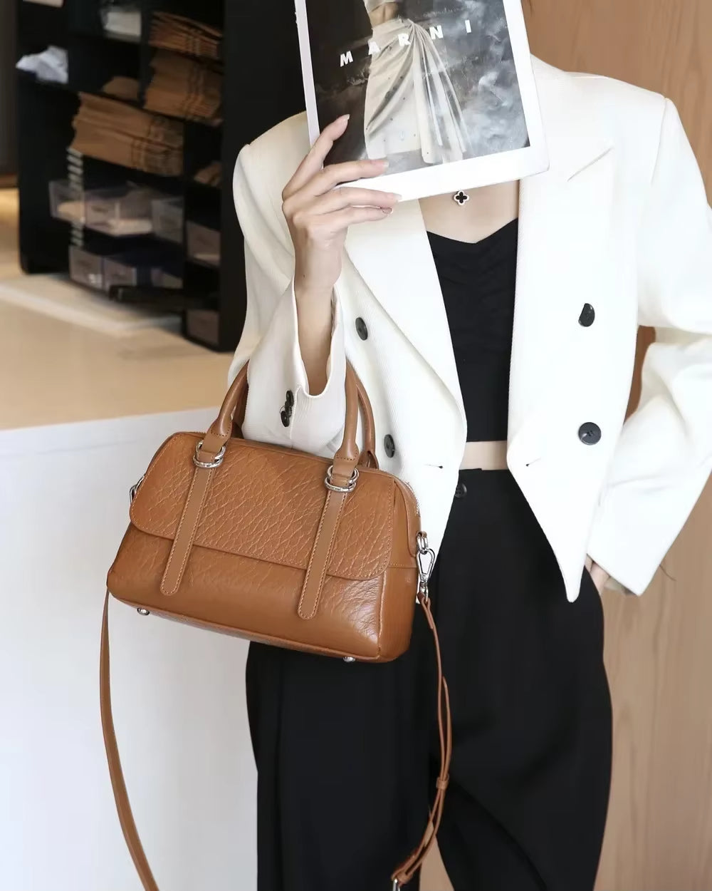 Donna con giacca bianca e borsa a tracolla marrone in pelle, elegante e moderna. Moda femminile, accessori di tendenza, abbigliamento chic.