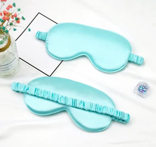 Mascherina per dormire in seta azzurra su sfondo bianco, con elastico arricciato. Accessorio per il sonno, relax, benessere.