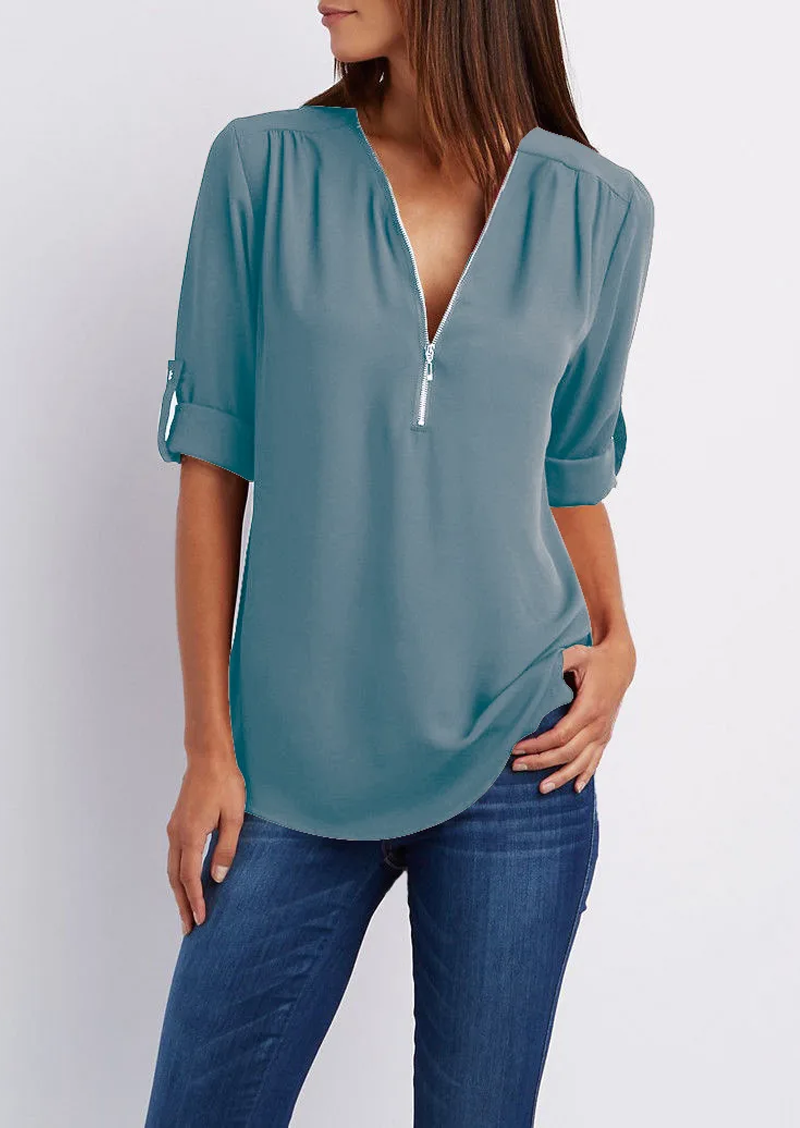 Blusa donna azzurra con zip frontale, maniche a 3/4 arrotolabili, abbinata a jeans. Elegante e casual, ideale per moda femminile quotidiana.