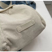 Borsa a tracolla in tessuto a coste beige, dettaglio etichetta in pelle. Accessorio moda casual, ideale per shopping e uso quotidiano.
