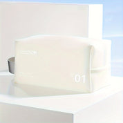 Elegante beauty case bianco con cerniera, design minimalista, ideale per viaggi. Accessorio da toilette compatto e moderno.