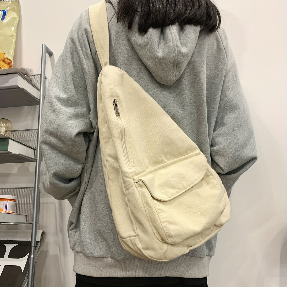 Zaino a tracolla beige su persona con felpa grigia, design casual e spazioso, ideale per scuola o viaggio. Accessorio moda unisex.