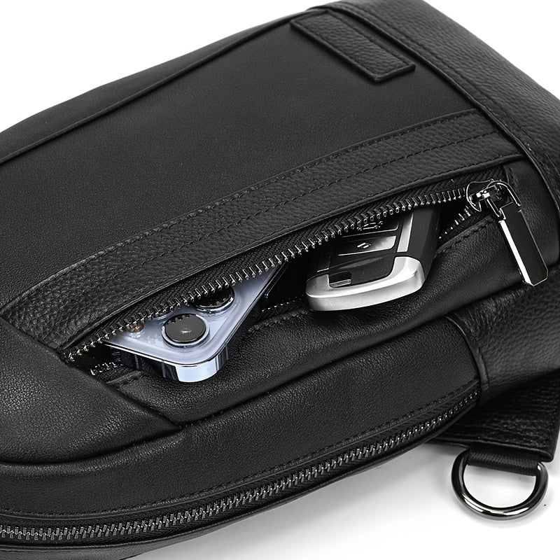 Marsupio nero in pelle con zip aperta, contenente smartphone e chiavi. Accessorio moda uomo, pratico e versatile per viaggi e uso quotidiano.