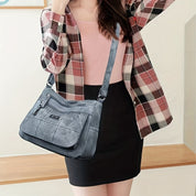 Donna con borsa a tracolla in denim blu, camicia a quadri e gonna nera. Moda casual femminile, accessorio trendy, stile urbano.
