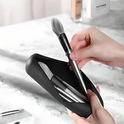 Mani che estraggono un pennello da trucco da un astuccio nero su un tavolo di marmo. Set pennelli cosmetici, accessori bellezza, trucco professionale.