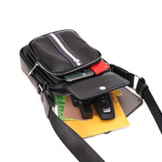 Borsa a tracolla in pelle nera con zip, contenente smartphone, chiavi, documenti e portafoglio. Design elegante e funzionale per uomo e donna.