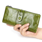 Portafoglio donna in pelle verde, chiusura a bottone, design elegante, tenuto in mano. Accessorio moda, alta qualità, ideale per shopping.