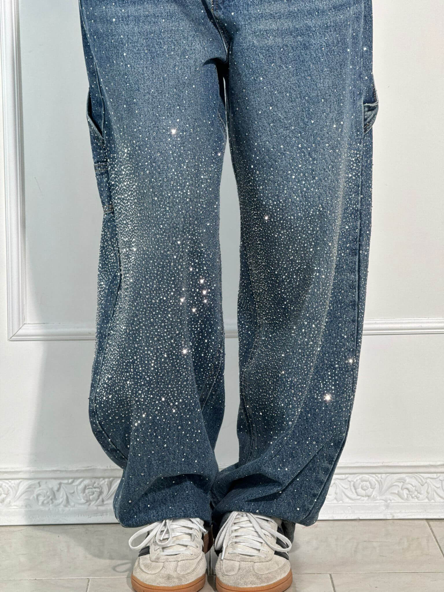 Jeans blu con strass scintillanti, stile casual, abbinati a scarpe da ginnastica bianche. Moda trendy, abbigliamento femminile, look glamour.