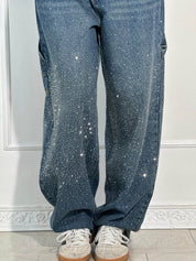 Jeans blu con strass scintillanti, stile casual, abbinati a scarpe da ginnastica bianche. Moda trendy, abbigliamento femminile, look glamour.