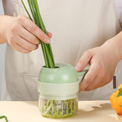 Tritatutto manuale verde in uso, taglia cipollotti freschi su un tavolo da cucina. Utensile da cucina pratico e compatto per verdure.