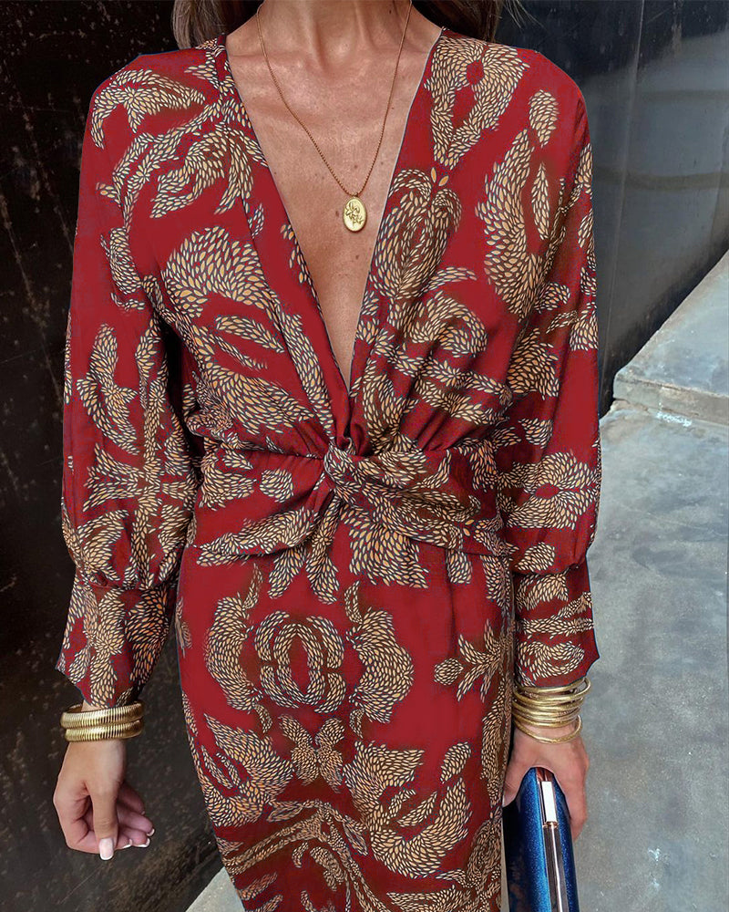 Abito rosso elegante con stampa floreale dorata, scollo a V profondo, maniche lunghe, accessori dorati, moda donna, stile sofisticato.