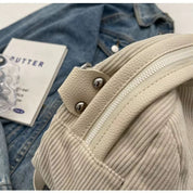 Zaino in pelle bianca su giacca di jeans, dettagli in metallo argentato, stile casual. Accessori moda, tendenze 2023, abbigliamento urbano.