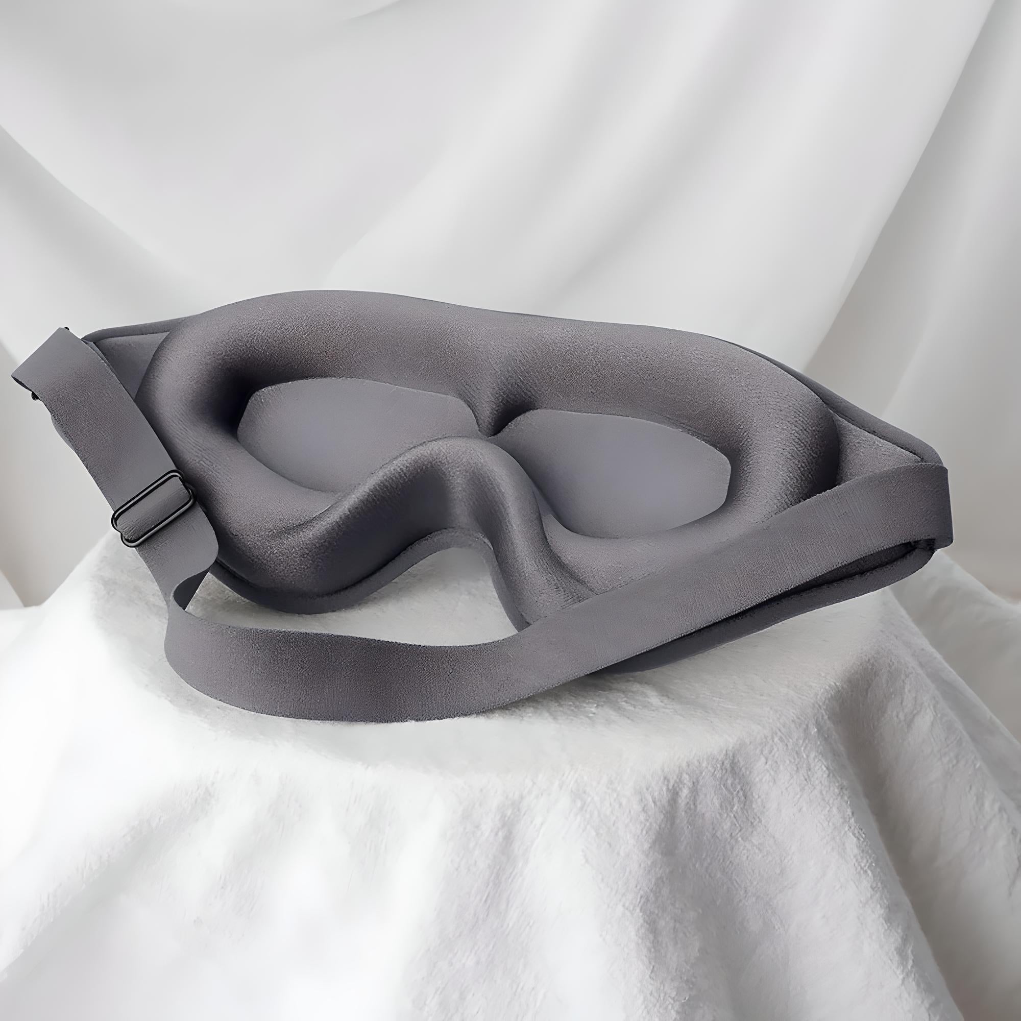 Maschera per dormire in memory foam grigia su sfondo bianco, design ergonomico, cinturino regolabile, comfort e blocco luce per un sonno profondo.