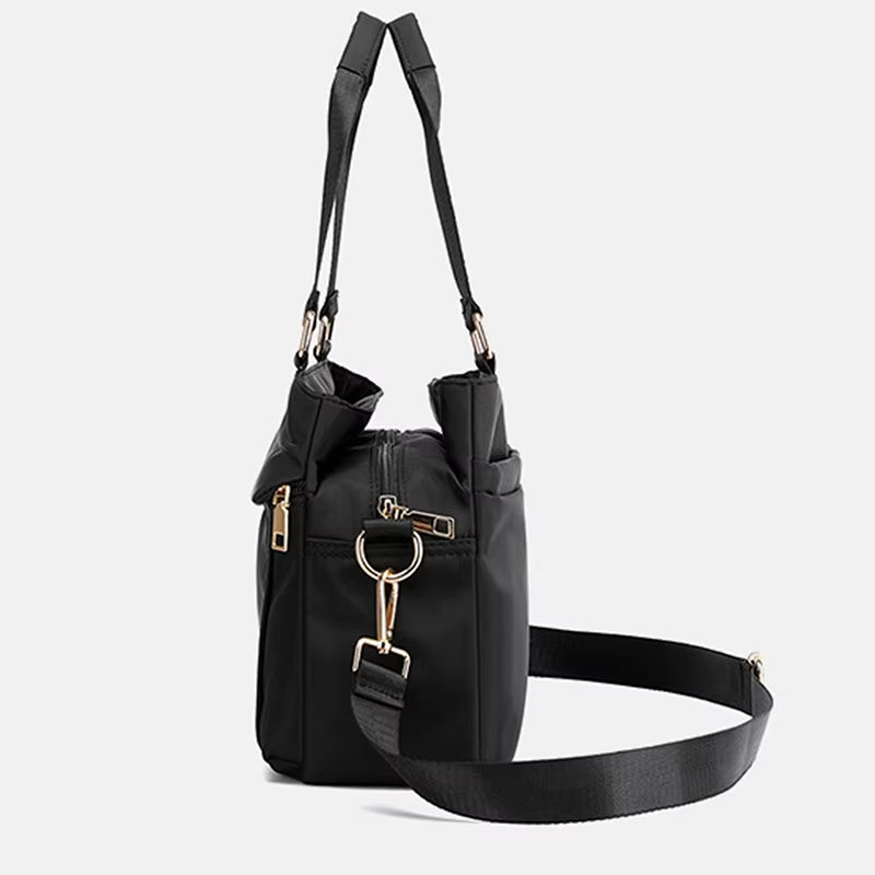Borsa a tracolla nera in pelle sintetica con dettagli in metallo dorato, chiusura con zip e tracolla regolabile. Design elegante e moderno.