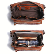 Borsa a tracolla in pelle marrone aperta, con scomparti interni contenenti tablet, libri, ombrello e portafoglio. Design elegante e funzionale.