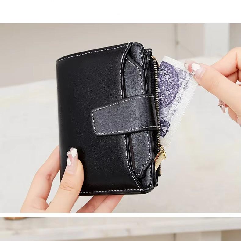 Portafoglio nero in pelle con chiusura a zip, design compatto, tenuto in mano. Ideale per donna, elegante e pratico per uso quotidiano.