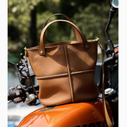 Borsa a mano in pelle marrone su moto arancione, design elegante e moderno, accessorio moda donna, perfetta per ogni occasione.