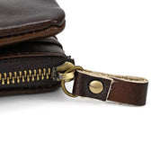 Portafoglio in pelle marrone con cerniera in metallo e tiralampo in pelle. Design elegante e resistente, ideale per uomo e donna.