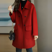 Cappotto rosso donna elegante, doppio petto, tasche frontali, abbinato a borsa nera a tracolla. Moda autunno inverno, abbigliamento femminile.