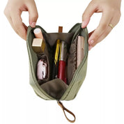 Borsa trucco verde aperta con cosmetici: rossetto, mascara, cipria. Organizzatore da viaggio compatto, accessori bellezza essenziali.