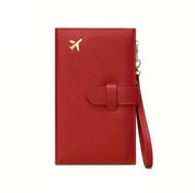 Portafoglio da viaggio rosso in pelle con icona dorata di aereo, cinturino da polso, design elegante e funzionale per passaporti e documenti.