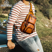 Uomo con borsa a tracolla in pelle marrone, stile casual, appoggiato a un'auto. Moda maschile, accessori eleganti, outdoor.