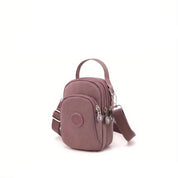 Borsa a tracolla piccola rosa con doppia cerniera, tasche multiple e cinturino regolabile. Design compatto, ideale per viaggi e uso quotidiano.