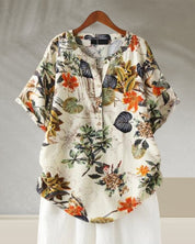 Camicia donna floreale, maniche corte, bottoni, sfondo bianco, stampa tropicale colorata. Moda estiva casual, tessuto leggero e traspirante.