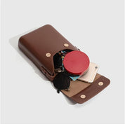 Custodia in pelle marrone con bottone, contenente occhiali da sole, smartphone e accessori. Design elegante e funzionale per organizzazione quotidiana.