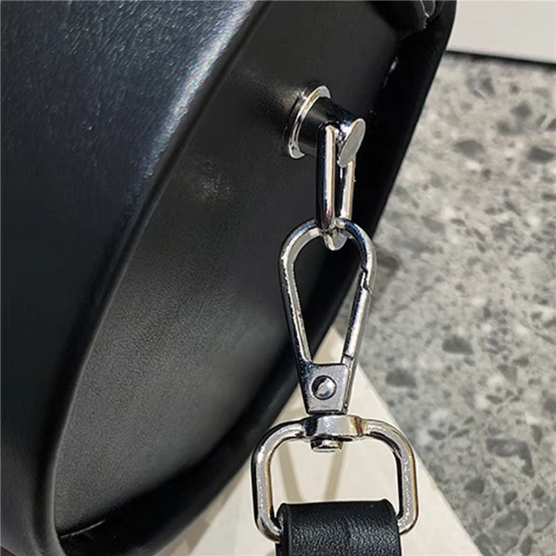 Gancio in metallo lucido su borsa in pelle nera, dettaglio di design elegante. Accessorio moda, alta qualità, stile contemporaneo.