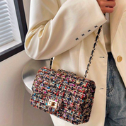 Borsa a tracolla in tessuto multicolore, indossata con giacca bianca. Design elegante, perfetta per moda autunnale e look casual chic.