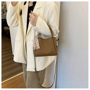 Giacca bianca elegante, borsa a tracolla marrone in pelle, outfit casual chic, moda donna autunno, accessori di tendenza, stile moderno.