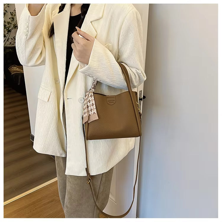 Giacca bianca elegante, borsa a tracolla marrone in pelle, outfit casual chic, moda donna autunno, accessori di tendenza, stile moderno.