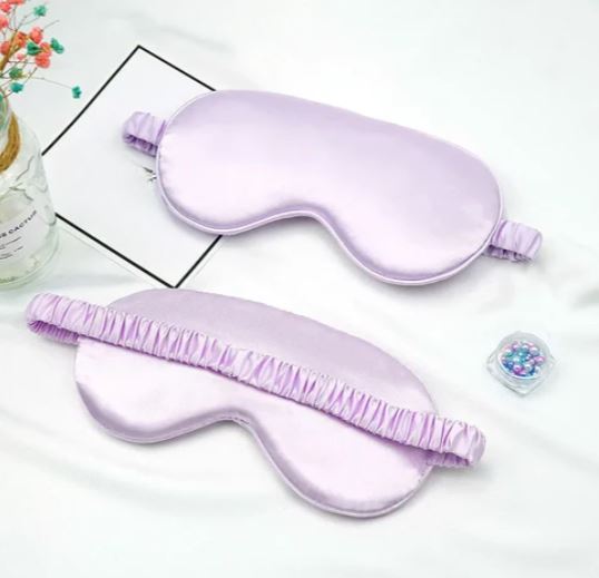 Mascherina per dormire in seta lilla su sfondo bianco, con elastico arricciato. Accessorio per il sonno, relax, benessere.