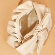 Borsa pochette in pelle beige con cerniera dorata e fiocco decorativo, design elegante e moderno, accessorio moda donna.